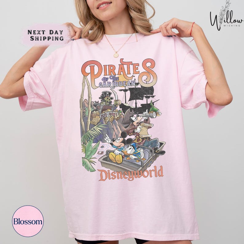 A woman wearing a pink t-shirt with a graphic of Disney characters from the Pirates of the Caribbean ride at Disneyworld.