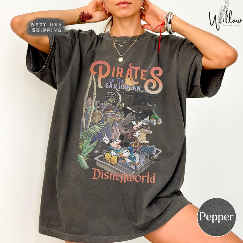 A person wearing a black t-shirt with a graphic of Disney characters from the Pirates of the Caribbean franchise.