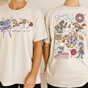 two white t-shirts with colorful cartoon characters and text printed on them.