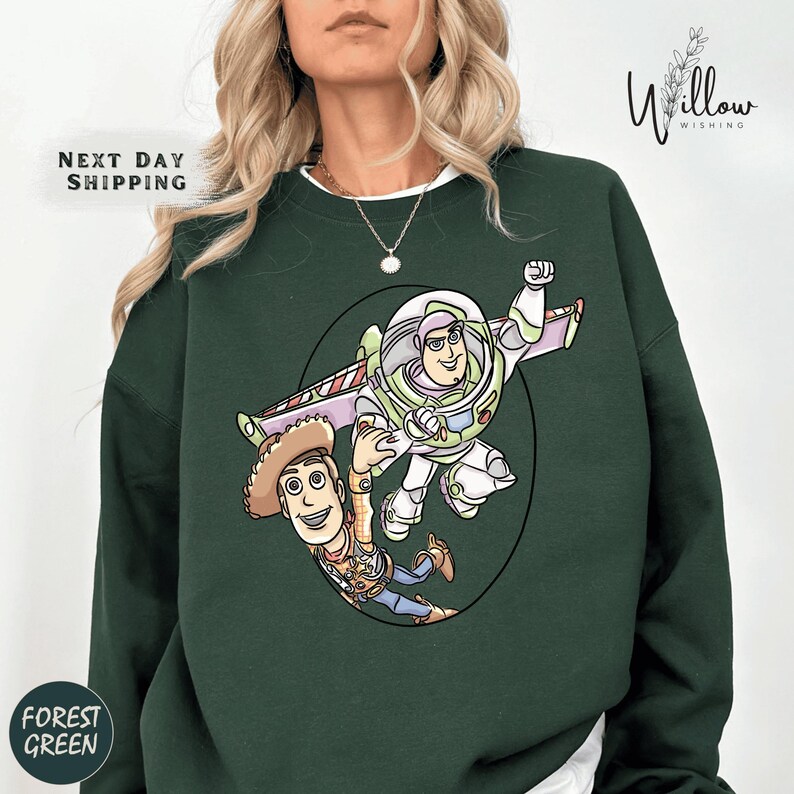 A woman wearing a green sweatshirt with a cartoon illustration of Buzz Lightyear and Woody from Toy Story.