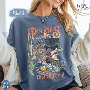 A woman wearing a blue t-shirt with a graphic of Disney characters from the Pirates of the Caribbean franchise.