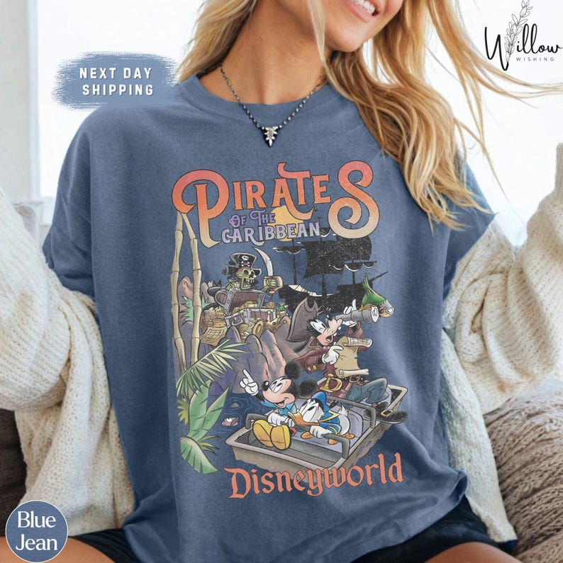 A woman wearing a blue t-shirt with a graphic of Disney characters from the Pirates of the Caribbean franchise.