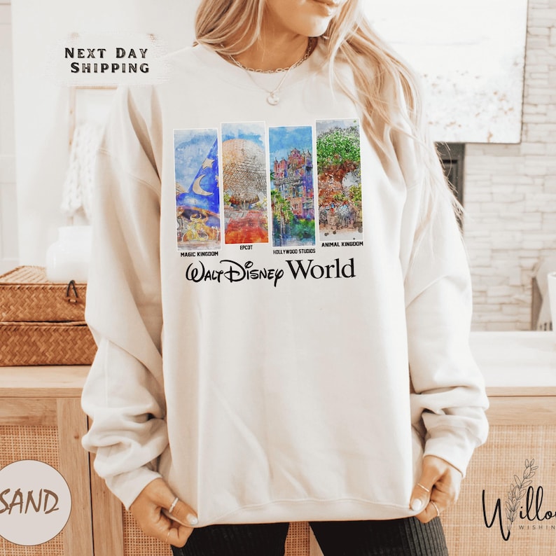 A woman wearing a white sweatshirt with a collage of four Disney World-themed images, including a castle, a roller coaster, a zoo, and a theme park.