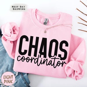 a pink sweatshirt with the words chaos over it