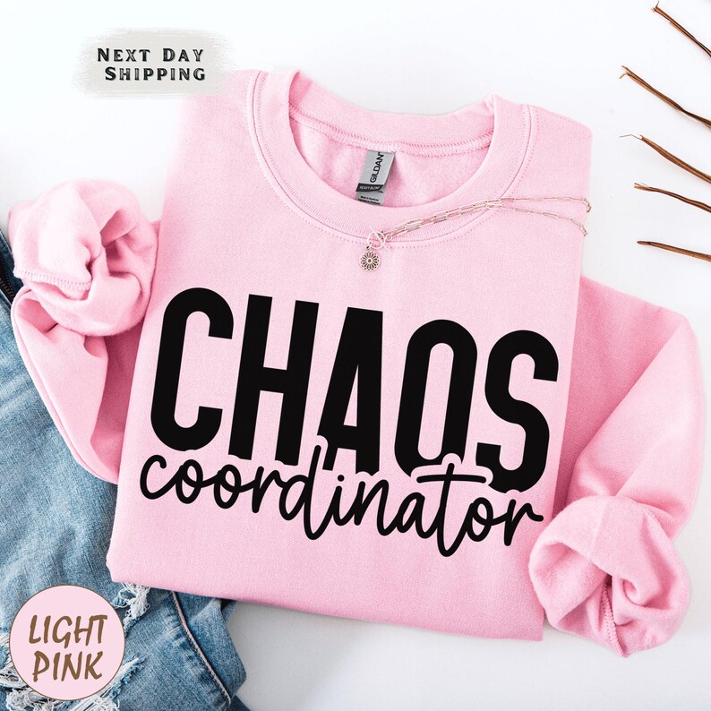 a pink sweatshirt with the words chaos over it
