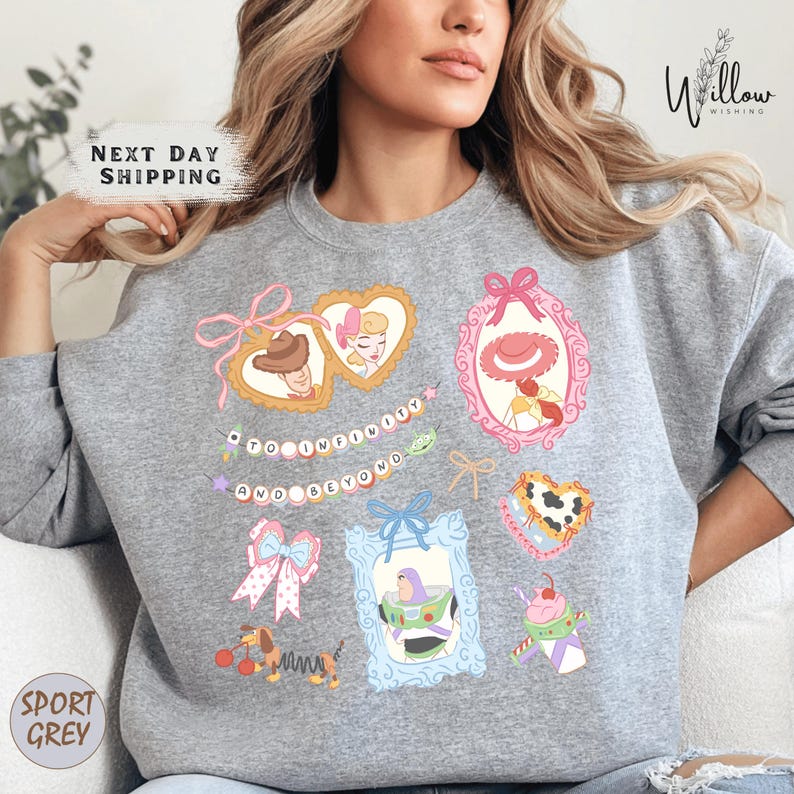 A woman wearing a gray sweatshirt with various cartoon-style illustrations and text printed on it.