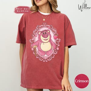 a woman wearing a red shirt with a pink bear on it
