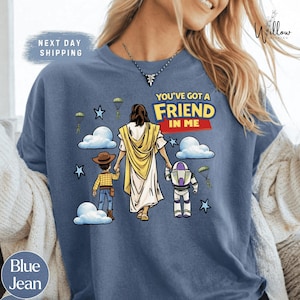A blue t-shirt with a graphic design depicting a person walking with a child and a robot, along with the text "You've got a FRIEND in me".