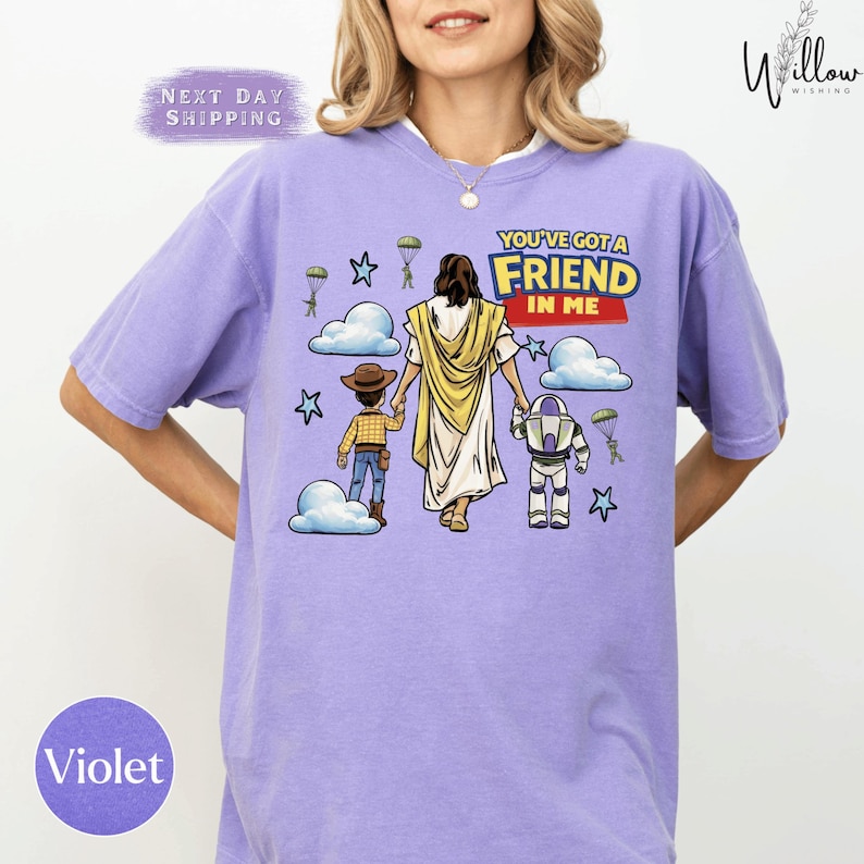 A woman wearing a purple t-shirt with a graphic design depicting a cartoon image of Jesus Christ holding a child and a robot.
