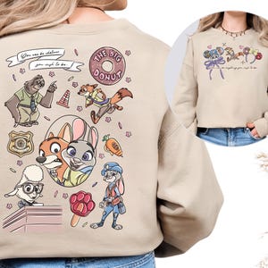 a person wearing a beige sweater with a cartoon-style design depicting various cartoon characters, including a police officer, a rabbit, and other animals.