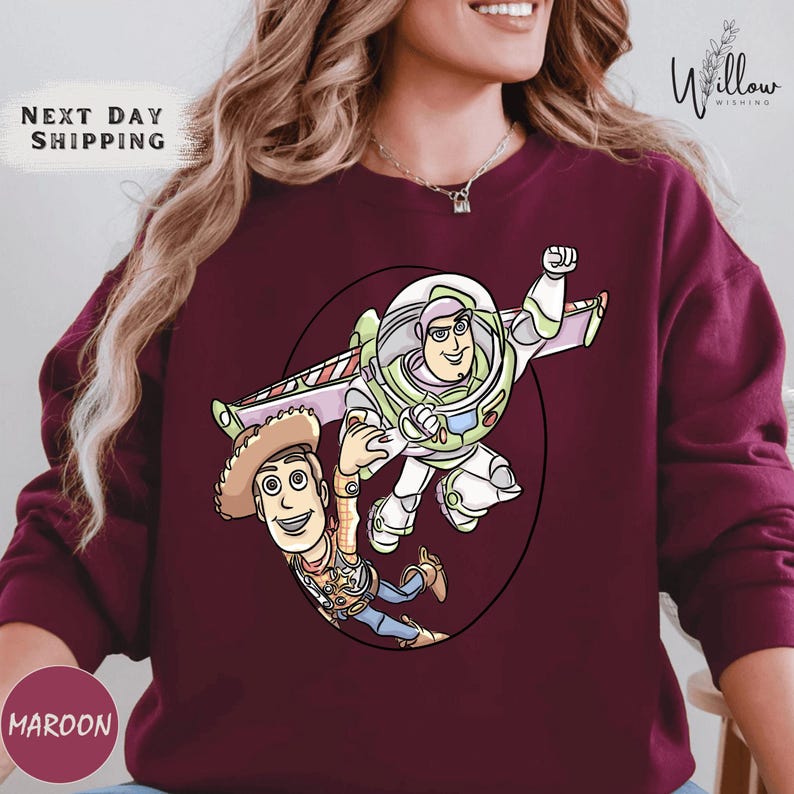 A woman wearing a burgundy sweater with a graphic of Buzz Lightyear and Woody from Toy Story printed on it.