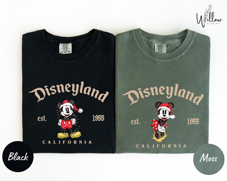two t-shirts with the same design, featuring a Mickey Mouse character and text that reads "Disneyland est. 1955 California". The t-shirts are in different colors: black and green.