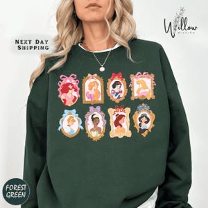 A woman wearing a green sweatshirt with a collage of illustrations of Disney princesses.