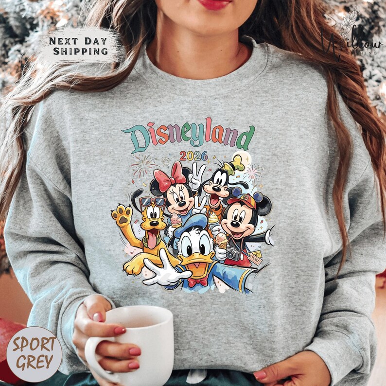 A woman wearing a gray sweatshirt with a colorful graphic of Disney characters from the theme park.