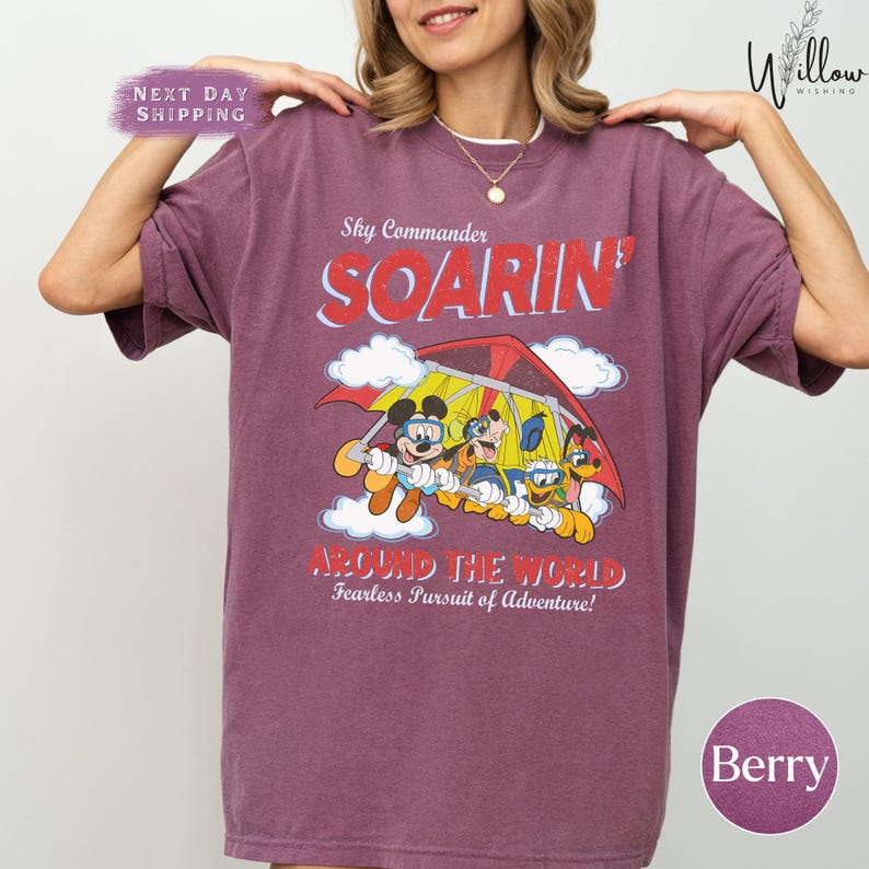 A woman wearing a purple t-shirt with a cartoon image of Mickey Mouse and Minnie Mouse on a red and yellow airplane.