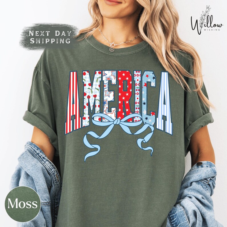 A woman wearing a green t-shirt with the word "AMERICA" printed on it, along with a bow and other patriotic symbols.