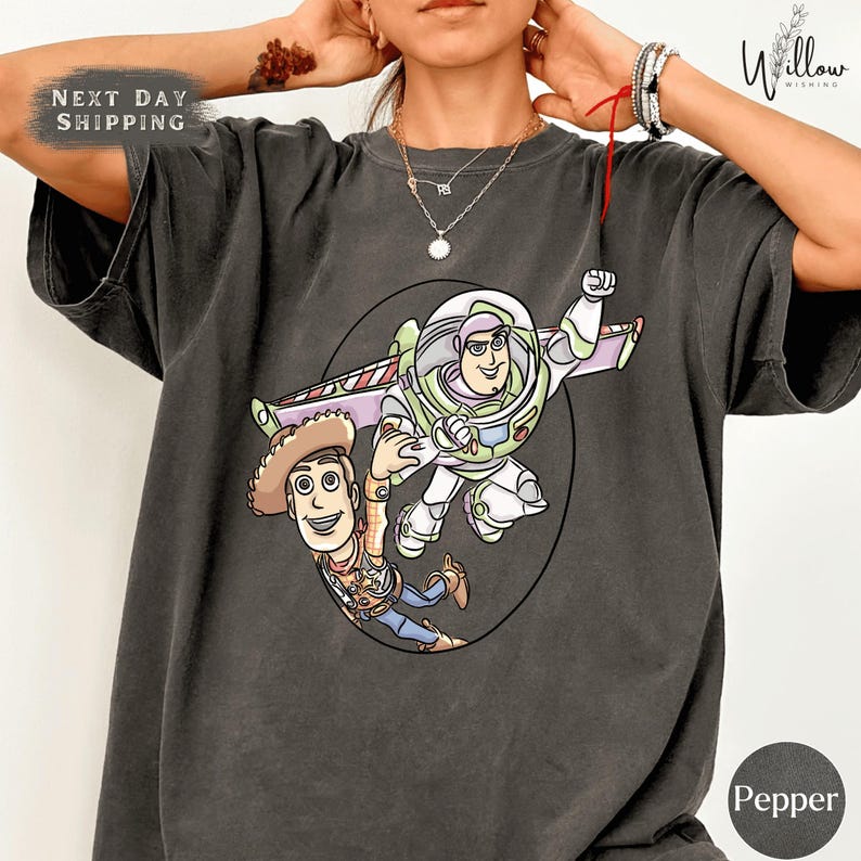 A person wearing a gray t-shirt with a graphic of Buzz Lightyear and Woody from Toy Story printed on it.