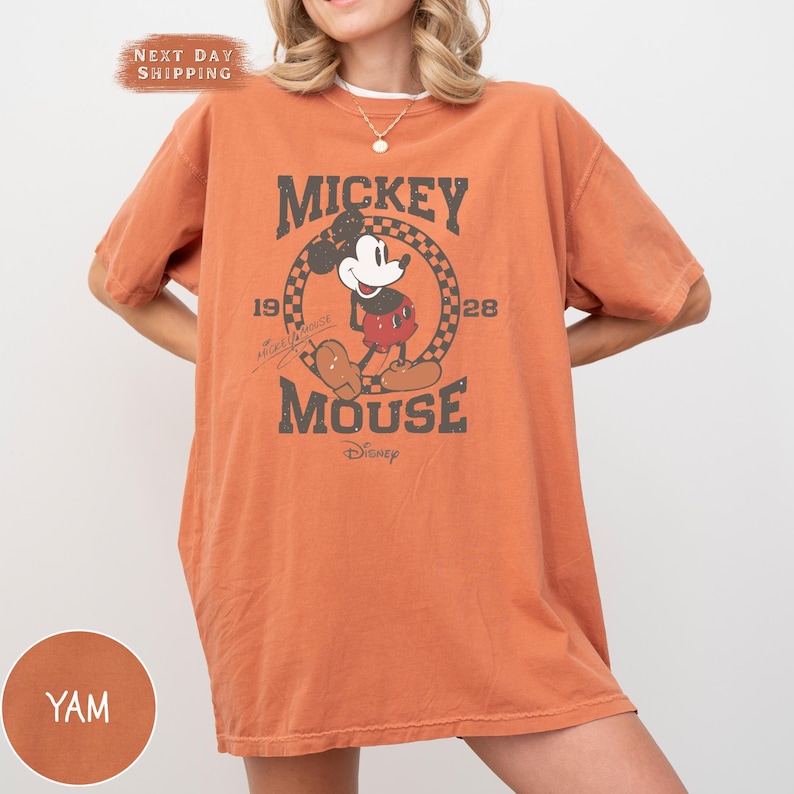 a woman wearing an orange mickey mouse t - shirt