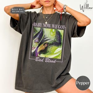 A person wearing a gray t-shirt with a graphic design featuring a character from the Disney film "Bad Blood".