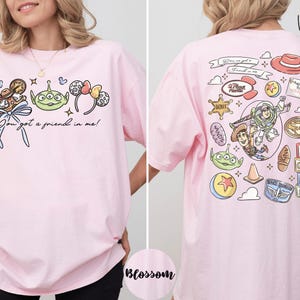 A woman wearing a pink t-shirt with various cartoon characters and text printed on it.