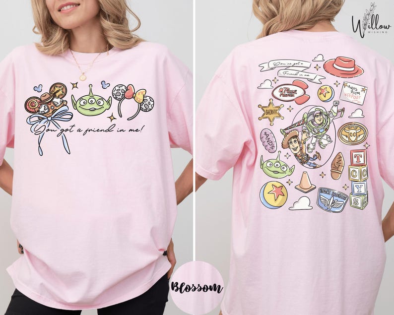 A woman wearing a pink t-shirt with various cartoon characters and text printed on it.
