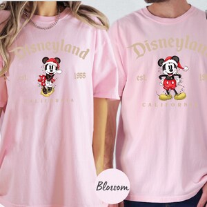 two people wearing matching pink t-shirts with the Disneyland logo and text.