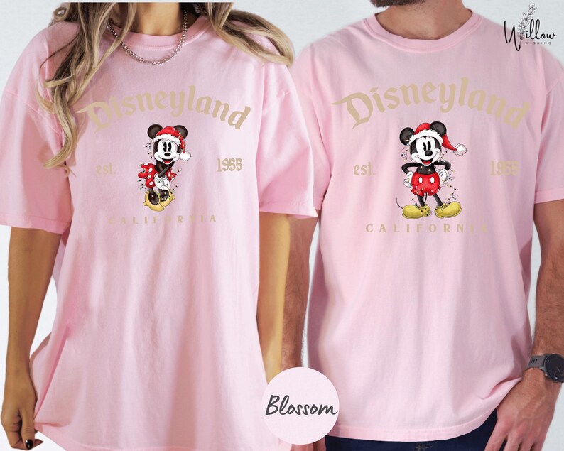 two people wearing matching pink t-shirts with the Disneyland logo and text.