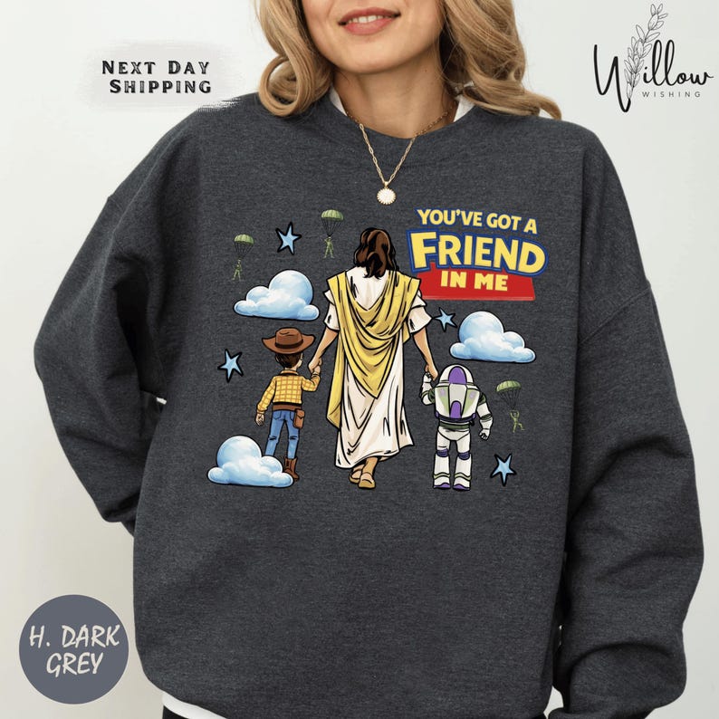 A woman wearing a gray sweatshirt with a graphic design depicting a religious figure, a child, and a character from the Toy Story franchise.