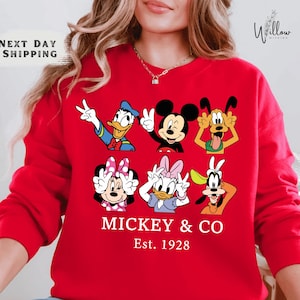 A woman wearing a red sweater with a graphic of Disney characters Mickey Mouse and Co.