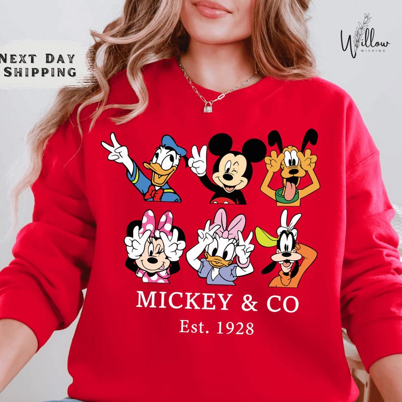 A woman wearing a red sweater with a graphic of Disney characters Mickey Mouse and Co.