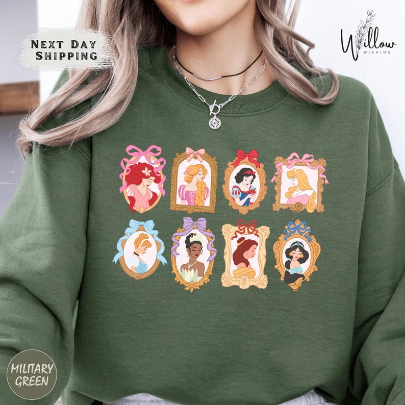 A woman wearing a green sweatshirt with a collage of illustrations of Disney princesses.