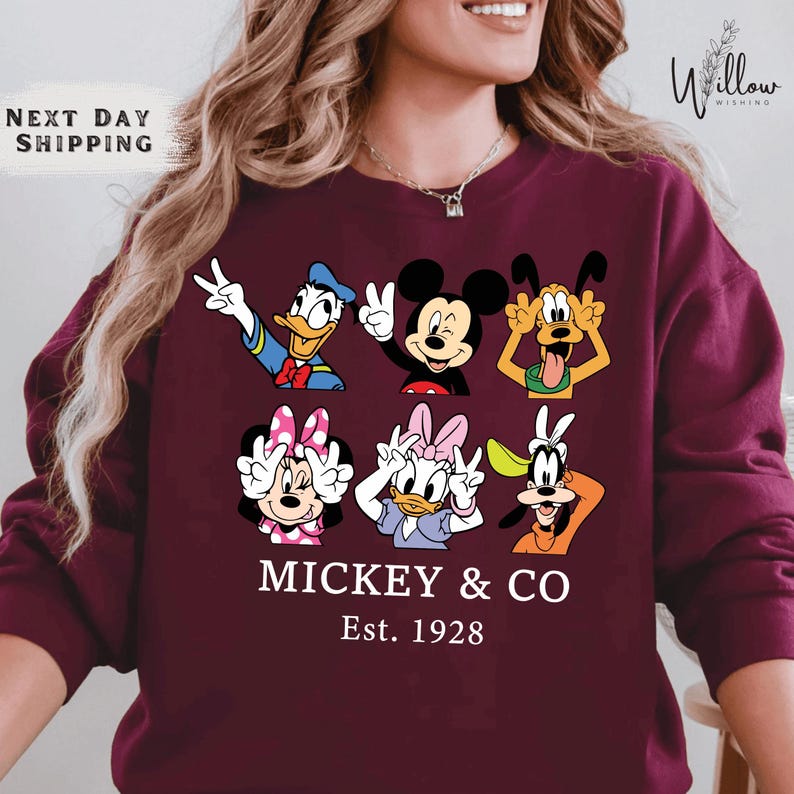 A woman wearing a maroon sweater with a graphic design featuring the Disney characters Mickey Mouse and Donald Duck.