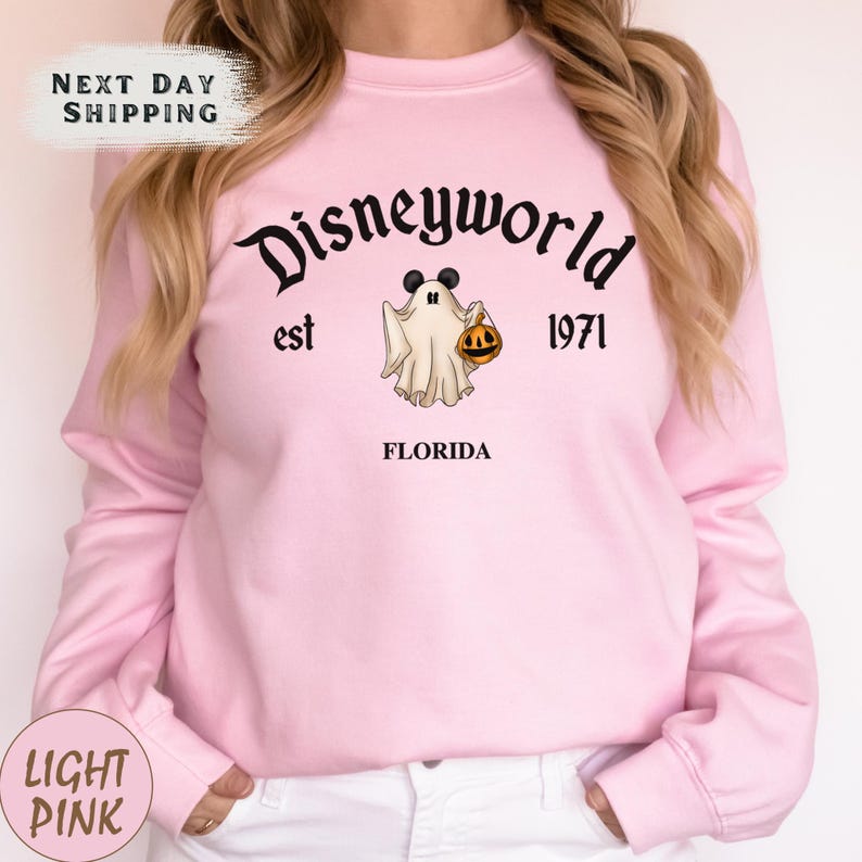 a woman wearing a pink disney world sweatshirt