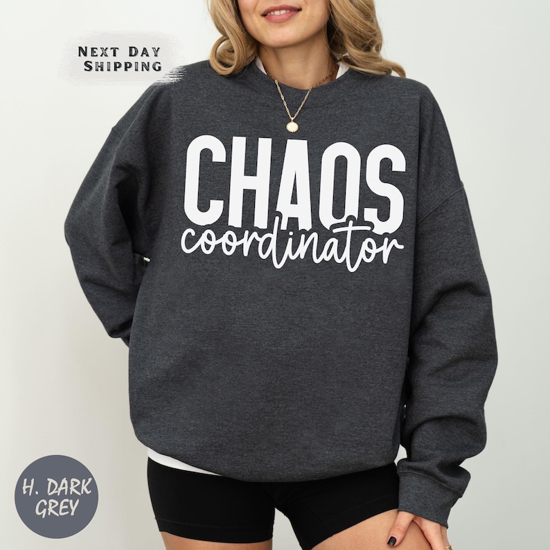 a woman wearing a black sweatshirt with the words chaos on it