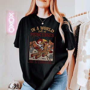 a woman wearing a shirt that says in a world for princesses be a cow