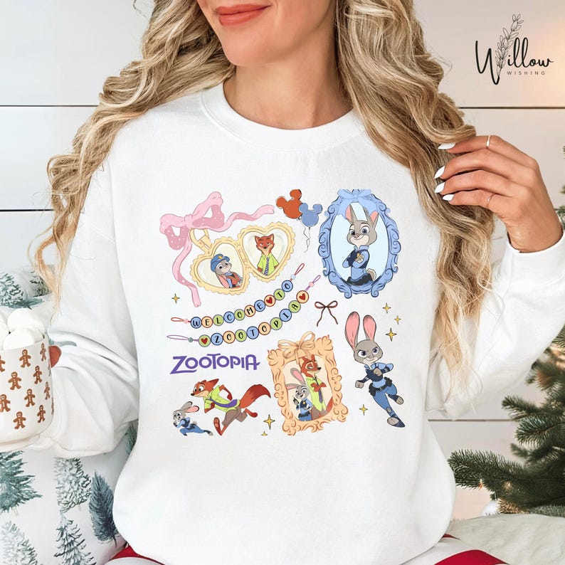 A woman wearing a white sweatshirt with a colorful graphic design featuring various cartoon characters from the movie "Zootopia".