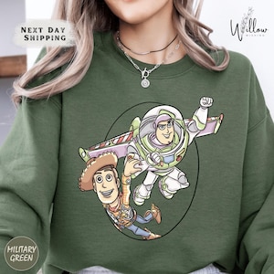 A green sweatshirt with a cartoon illustration of Buzz Lightyear and Woody from Toy Story.