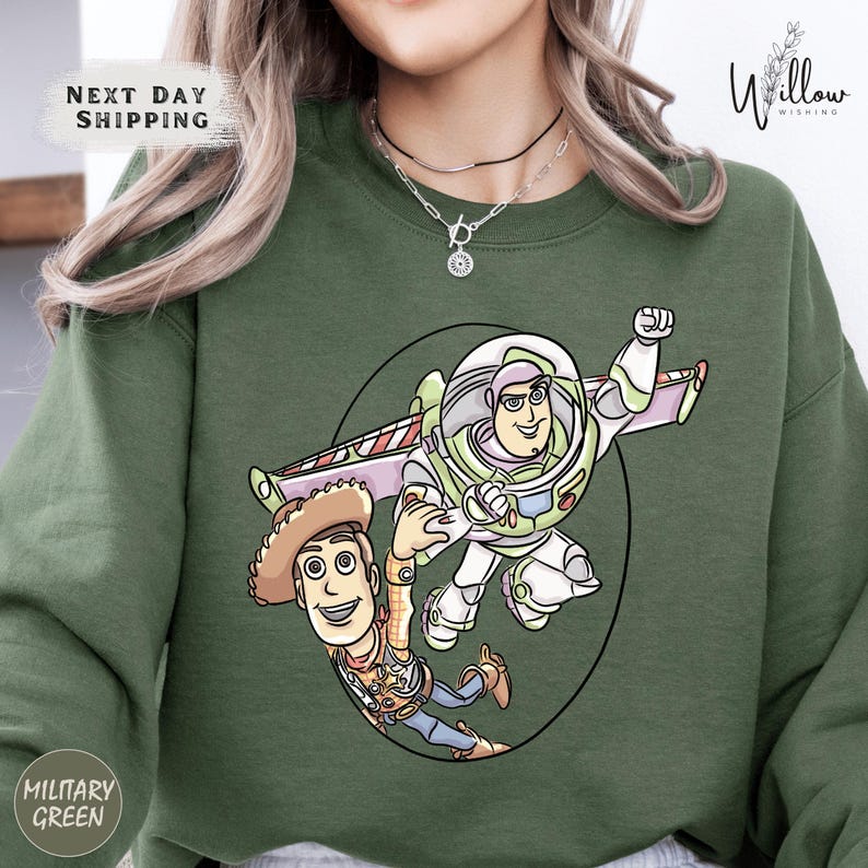 A green sweatshirt with a cartoon illustration of Buzz Lightyear and Woody from Toy Story.
