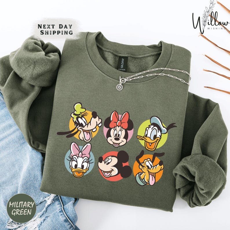 A green sweatshirt with a graphic of Disney characters, including Goofy, Minnie Mouse, Donald Duck, Mickey Mouse, Donald Duck's ducklings, and Pluto, arranged in a circular pattern.