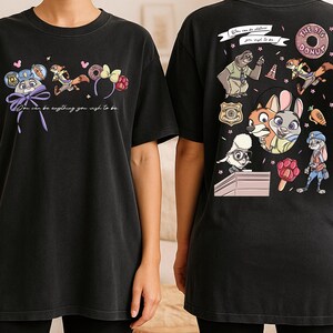 two black t-shirts with colorful cartoon characters and text printed on them.