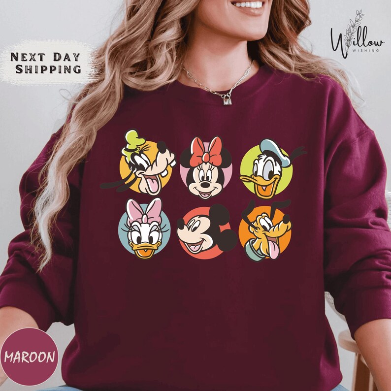 A woman wearing a burgundy sweater with a graphic of Disney characters on it.
