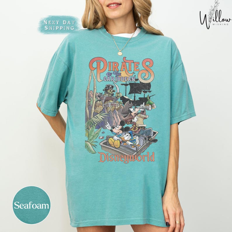 A woman wearing a turquoise t-shirt with a graphic of Disney's Pirates of the Caribbean on it.