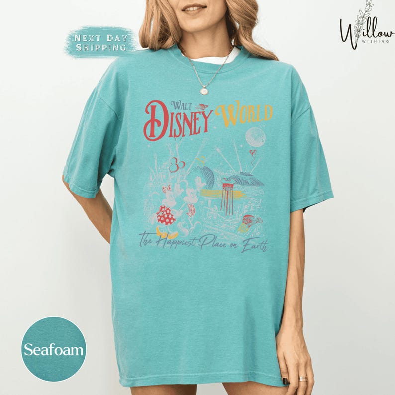 A woman wearing a turquoise t-shirt with a graphic design of Disney characters and text promoting Walt Disney World.