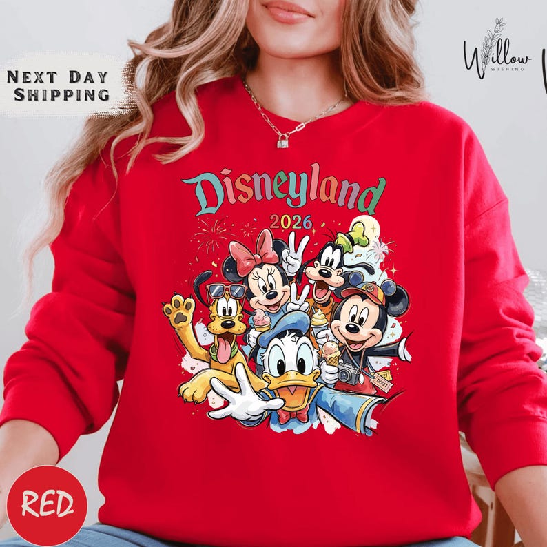 A woman wearing a red sweater with a Disney-themed graphic of Minnie Mouse, Donald Duck, Mickey Mouse, and Goofy.