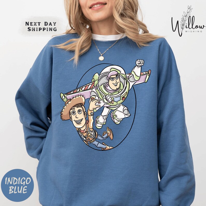 A woman wearing a blue sweatshirt with a cartoon image of Buzz Lightyear and Woody from Toy Story printed on it.
