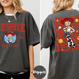 a woman wearing a gray t-shirt with a design of a character from the Toy Story franchise.