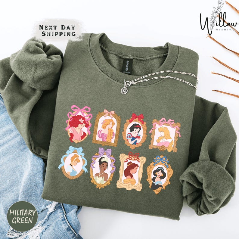 a green sweatshirt with a graphic design of various Disney princesses, including Snow White, Rapunzel, and other popular characters.