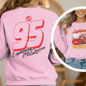 A woman wearing a pink sweatshirt with the number 95 and the text "Lightning McQueen" printed on it.