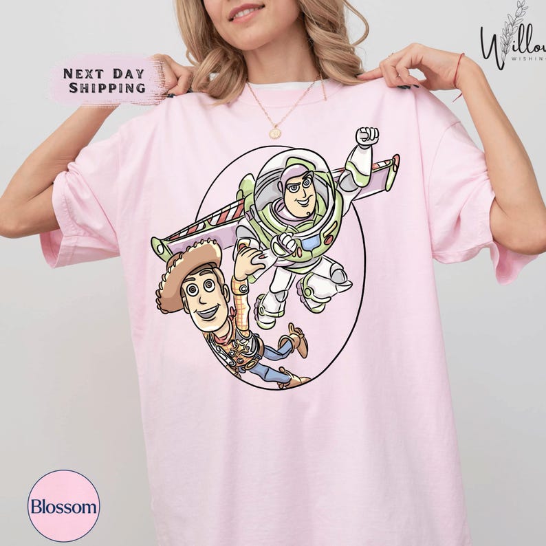 A woman wearing a pink t-shirt with a cartoon character from the Toy Story franchise, specifically Buzz Lightyear and Woody, printed on it.