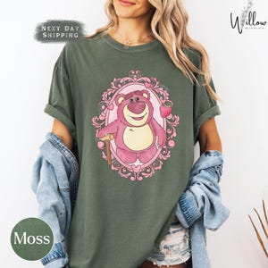 a woman wearing a green shirt with a pink bear on it